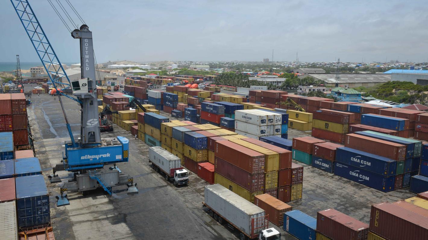 An aerial view of shipping containers, trucks and a large crane