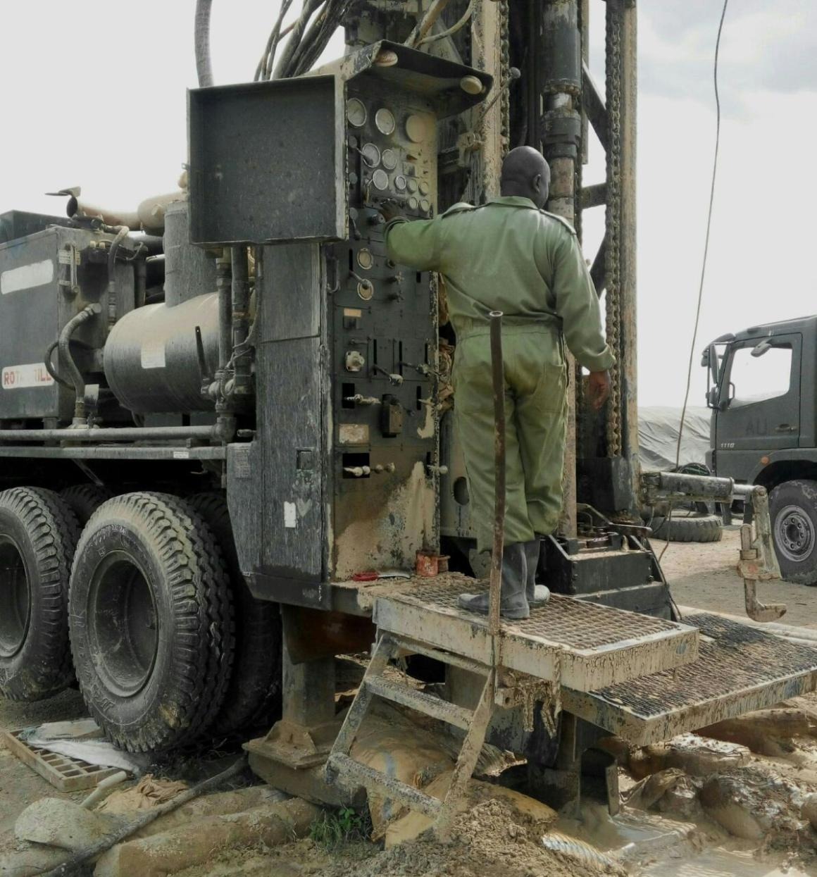 A man stands on a large piece of water drilling equipment